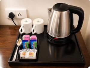 a black tray with a coffee pot and packets of tea at EMBLEM Hotel - Arjun Marg, Golf Course Road, Gurgaon in Gurgaon