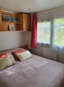 a bed with two pillows in a bedroom with a window at Mobile Home in Morbier