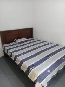 a bed with a blue and white striped comforter at Down Fattna Eco Villa in Deniyaya