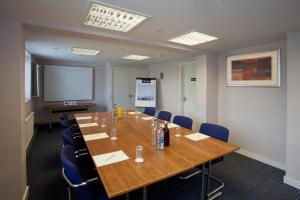 une salle de conférence avec une grande table en bois et des chaises bleues dans l'établissement Britannia Hotel Bolton, à Bolton