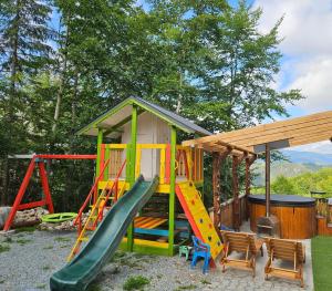 a playground with a slide and a house at Casa din fagi in Munună