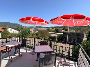 two tables and chairs with umbrellas on a balcony at Appartement spacieux et lumineux proche gare in Ambérieu-en-Bugey