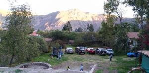 a group of cars parked in a yard with a mountain at Valles Apartamentos Ecológicos VAE - Urubamba Cusco Perú in Urubamba