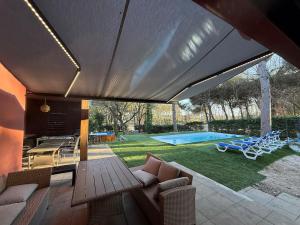 a patio with a couch and a table and a pool at Casa Natura Flassia de 240m2 con piscina privada in Vidreres