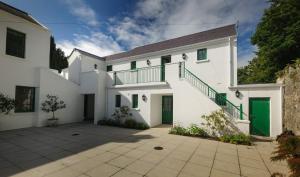 a white house with green doors and a courtyard at Milntown Self Catering Apartments in Ramsey