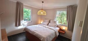 a bedroom with a bed and two windows at Lavendelhaus am Müritzsee - direkt am Wasser in Buchholz