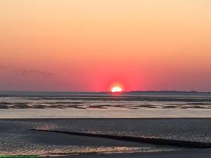 a sunset over the ocean with the sun in the horizon at Emes Stuuv in Oevenum
