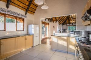a large kitchen with white appliances and wooden cabinets at Ambleside Cottage in Underberg