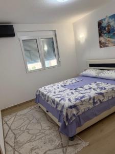 a bedroom with a bed and two windows at Lux apartment in Dobra Voda