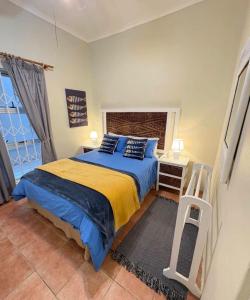 a bedroom with a bed with blue sheets and a window at Kei Sands Nr 6 in Kei-mouth Village