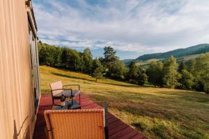 a patio with two chairs and a table on a house at Tiny House Dolinky in Veľká Lesná