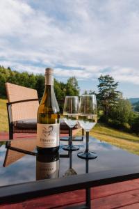 a bottle of wine and two wine glasses on a table at Tiny House Dolinky in Veľká Lesná