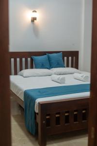 a bed with blue and white sheets and pillows at Villa Downsouth Nilaveli in Kumpurupiddi
