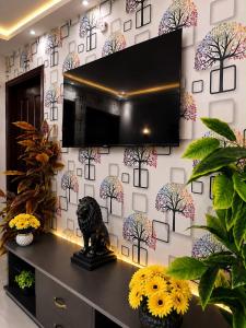 a tv on a wall in a room with flowers at Family-Friendly Luxury Apartment Home Away From Home in Islamabad