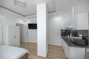 a white room with a bed and a counter with a microwave at L&S House in Prague