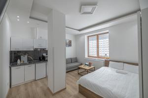 a white bedroom with a bed and a kitchen at L&S House in Prague
