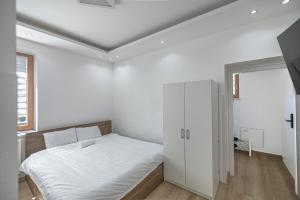 a white bedroom with a bed and a window at L&S House in Prague