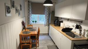 a kitchen with a table and a sink and a table and chairs at Tornyai Apartman in Hódmezővásárhely +8 photos
