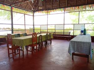 a dining room with tables and chairs and windows at Amazon Lodge and Expeditions in Iquitos