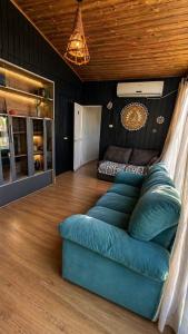 a living room with a blue couch and a bed at Pousada Cristais do Rosa in Imbituba