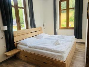 a bedroom with a wooden bed with white sheets at Celnice pod Sněžníkem-Nová Seninka in Staré Město