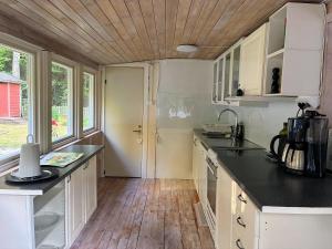 a kitchen with white cabinets and a wooden ceiling at Sjönära stuga in Norrtälje