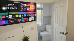 a bathroom with a toilet and a tv on the wall at New Horizon Lodge in Leigh