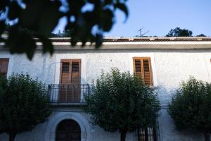 a white building with orange shuttered windows and trees at La Vista Colliano in Colliano
