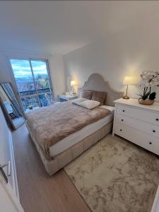 a white bedroom with a large bed and a window at Superbe appart chic & élegant 2ch - 6 pers in Deuil-la-Barre