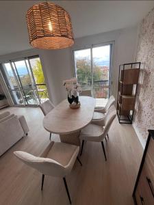 a dining room with a table and chairs and a room with windows at Superbe appart chic & élegant 2ch - 6 pers in Deuil-la-Barre