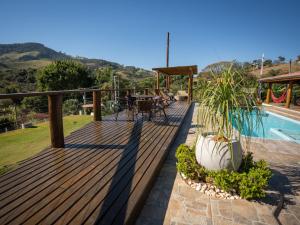 a wooden deck with a pool and a table and chairs at Chácara Pimenta Vermelha in Socorro