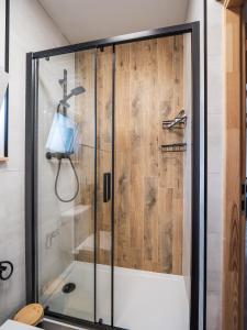 a shower with a glass door in a bathroom at SierPlejs Hill - domki przy szlaku w Górach Sowich in Sierpnica +36 photos