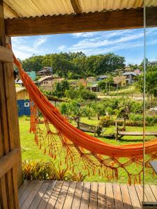 a hammock on a porch with a view of a field at Pousada Cristais do Rosa in Imbituba