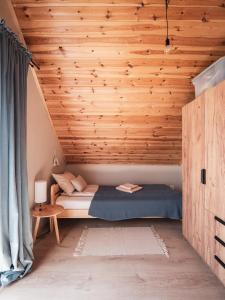 a bed in a room with a wooden ceiling at SierPlejs Hill - domki przy szlaku w Górach Sowich in Sierpnica