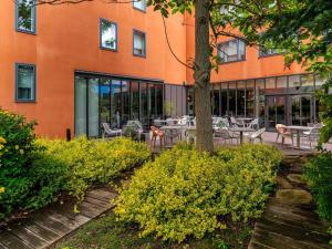 an orange building with tables and chairs in front of it at Novotel Suites Reims Centre in Reims