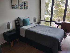a bedroom with a bed and a desk and a window at Acogedor y moderno departamento in Mexico City
