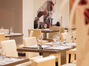 a man standing in a dining room with tables with wine glasses at ibis Lyon Est Chaponnay in Chaponnay
