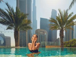 a woman sitting in a swimming pool in a city at Sofitel Dubai Downtown in Dubai
