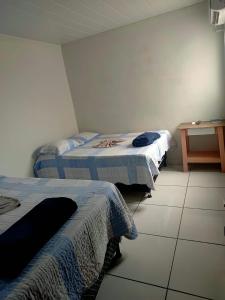 two beds in a room with a tiled floor at Hotel Boneario in Vitória da Conquista