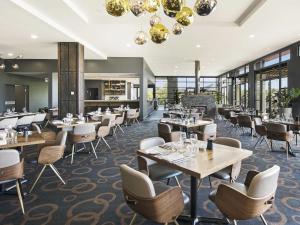 a restaurant with tables and chairs and windows at Mercure Kooindah Waters Central Coast in Wyong