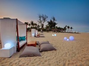 a canopy bed on a sandy beach at Pullman Danang Beach Resort in Danang