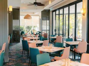 a dining room with tables and chairs and windows at Mercure Gold Coast Resort in Gold Coast