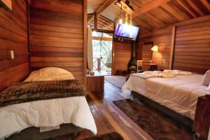 a bedroom with two beds and a tv in it at Chalé Monte Rei in Monte Verde