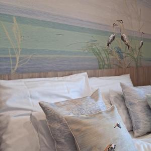 a bed with white pillows and a painting of birds at Levendula Apartman in Buzsák