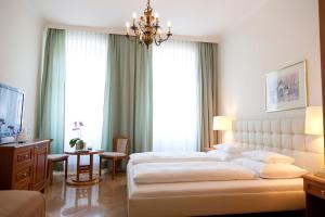 a large bedroom with two beds and a chandelier at Hotel Schwalbe in Vienna