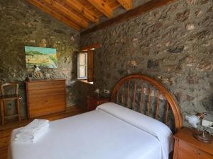 a bedroom with a bed and a stone wall at Cal Ferrer del Querforadat in Cava
