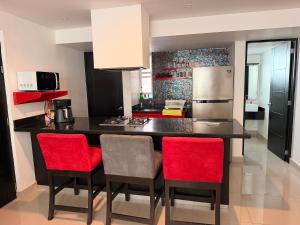 a kitchen with a black counter and red chairs at Departamento Conjunto Mirador in Santa Cruz Huatulco