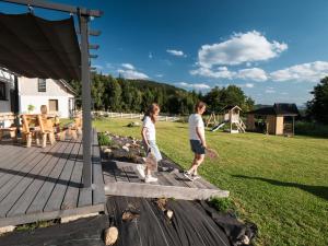 a man and a woman standing on a wooden deck at SierPlejs Hill - domki przy szlaku w Górach Sowich in Sierpnica