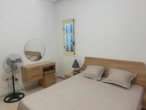 a bedroom with a bed and a mirror and a fan at Résidence Djerba Oasis in Mezraya +36 photos