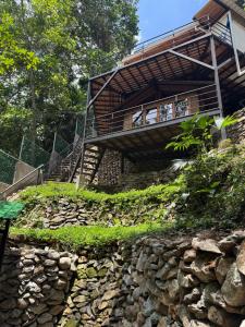 a building on a hill with a stone wall and stairs at SeTena Tierra Humeda Ecolodge in Minca